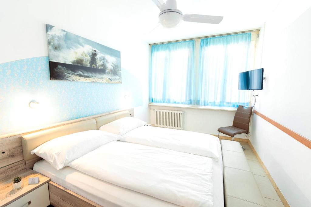 卢加诺Hotel San Carlo的卧室配有白色的床和椅子
