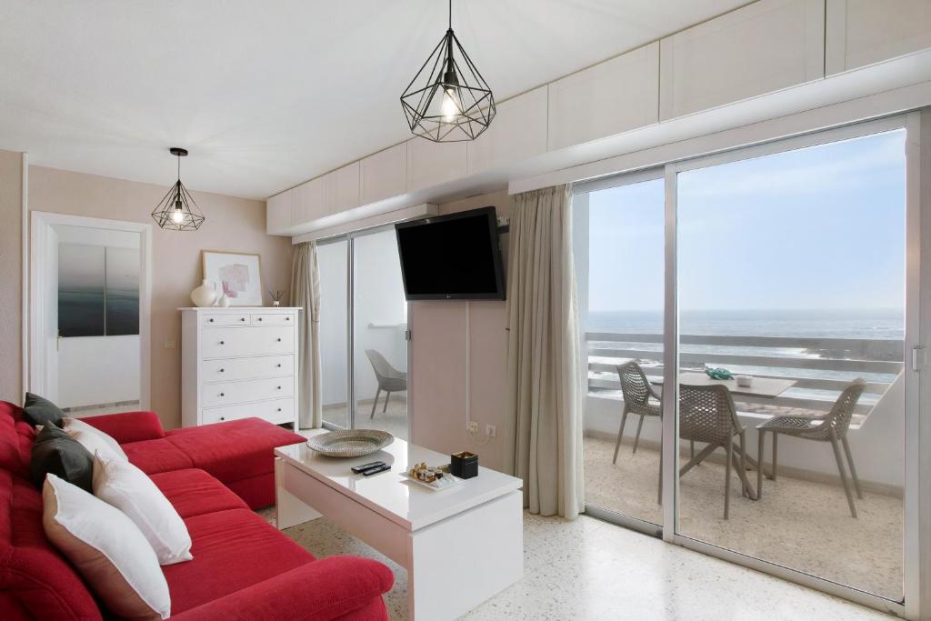 塔科龙特Apartamentos Tamara的客厅配有红色沙发,享有海景