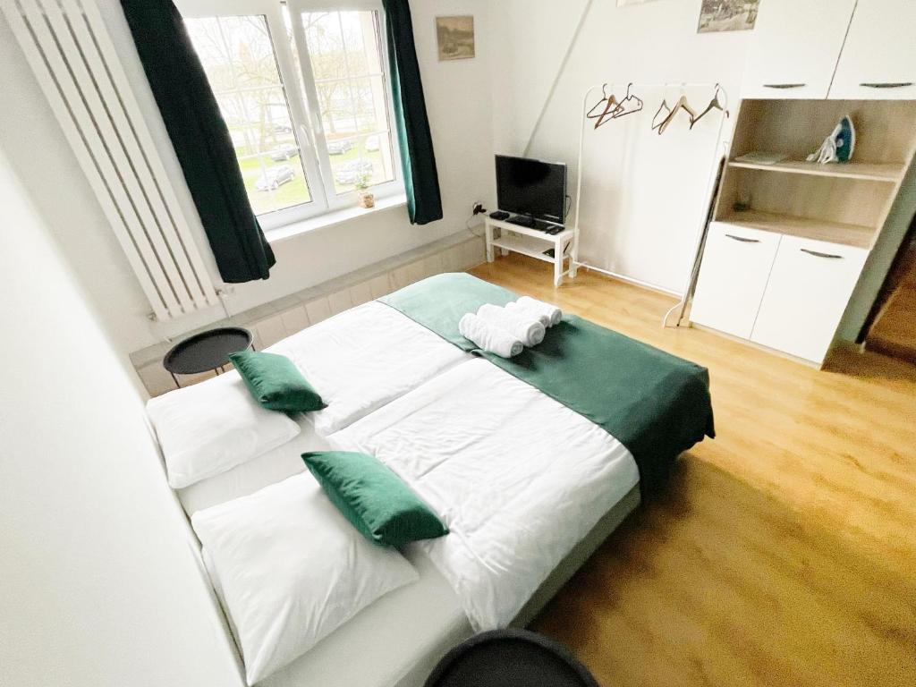 马尔堡Główna Apartamenty Nad Nogatem的卧室配有带绿色枕头的大型白色床