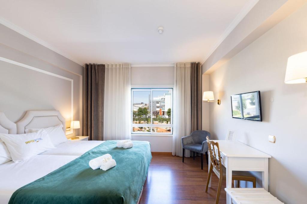 法蒂玛Imperhotel by Umbral的配有一张床、一张书桌和一扇窗户的酒店客房