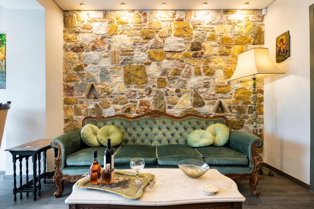 雅典Queen's stone legend, royal living by Acropolis的客厅设有绿色沙发和石墙