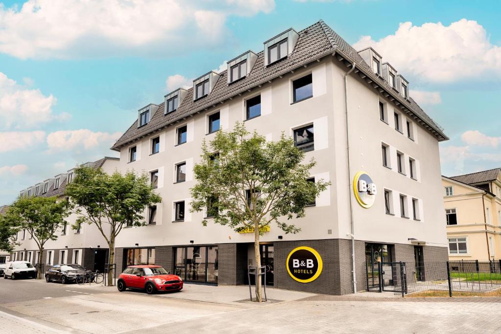 吉森B&B Hotel Gießen的一座白色的建筑,前面有一辆红色的汽车