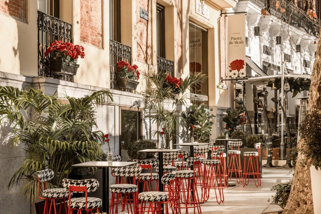 马德里Hospes Puerta de Alcalá, a Member of Design Hotels的一条种满植物的街道上一排桌椅
