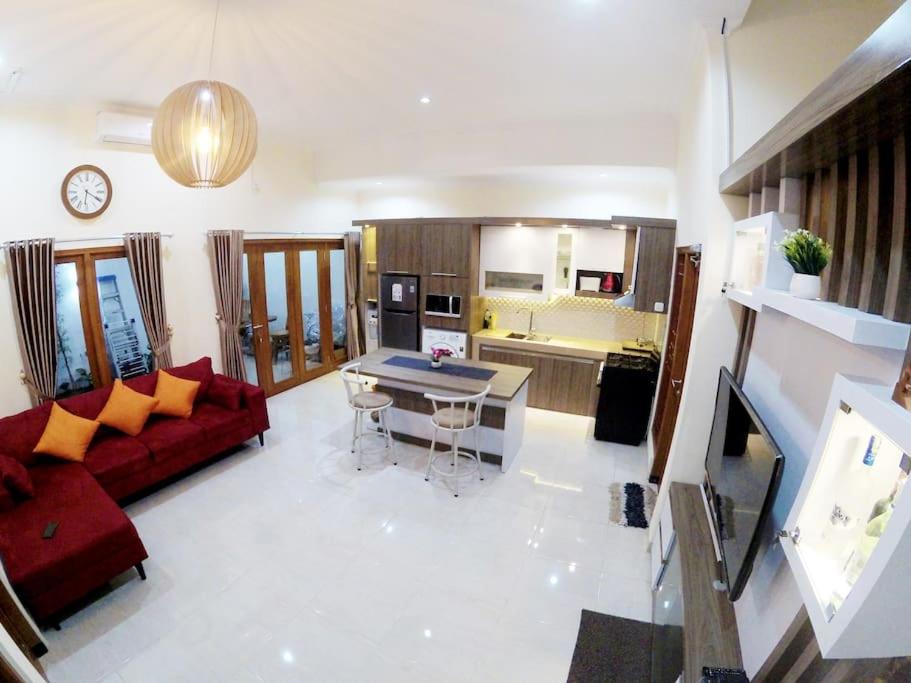KalasanRumah Bungur, Purwomartani的一间带红色沙发的客厅和一间厨房