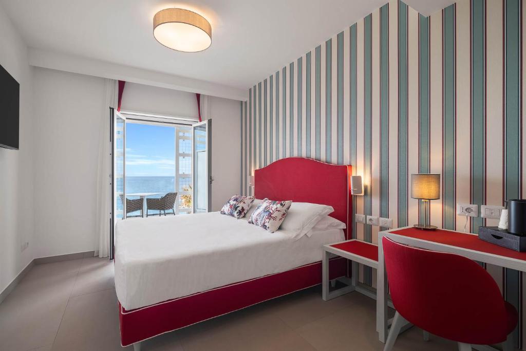 卡普多兰多Seaside Hotel的一间卧室配有一张带红色床头板的床和窗户