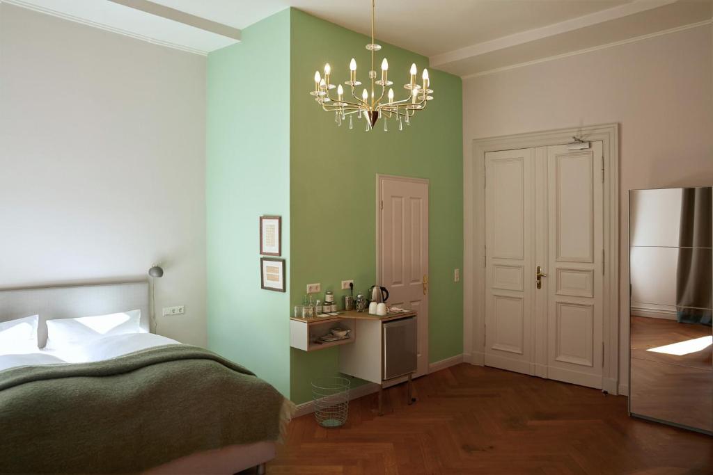 柏林Wil7 Boutique Hotel的一间卧室设有绿色的墙壁、一张床和一个吊灯。