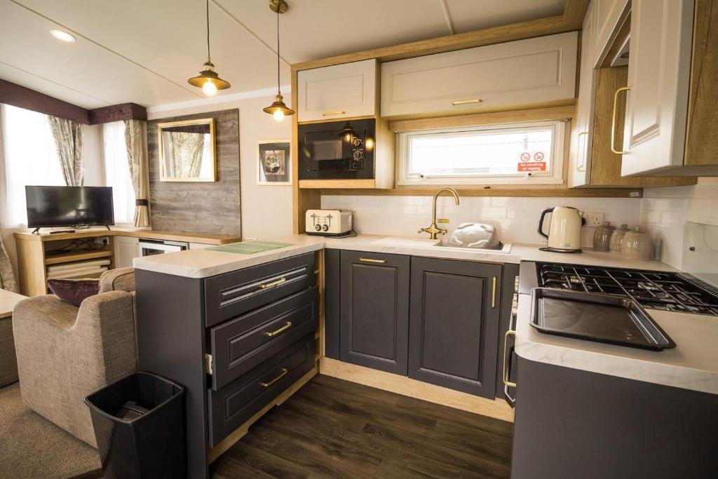 大雅茅斯Modern Caravan At Caldecott Hall With Decking In Norfolk, Sleeps 8 Ref 91068c的厨房配有水槽和炉灶 顶部烤箱