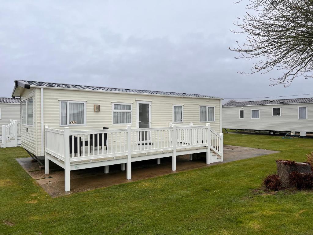 米尔福德昂西Home by the sea, Hoburne Naish Resort, sleeps 4, on site leisure complex available的白色移动房屋 - 带门廊和庭院