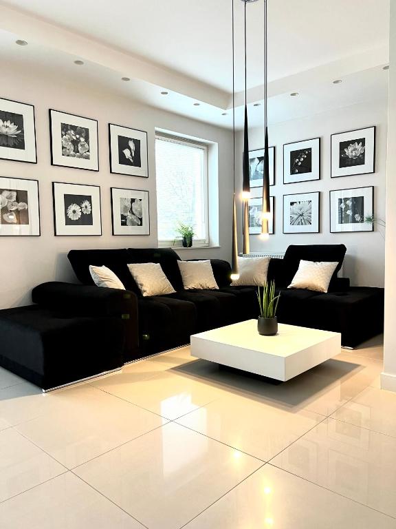 绿山城Spanko w centrum的客厅配有黑色沙发和白色桌子