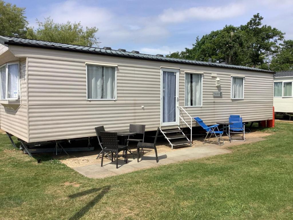 亨斯坦顿6 Berth Caravan For Hire In Hunstanton At Manor Park Holiday Park Ref 23004a的前面有带椅子和桌子的大篷车