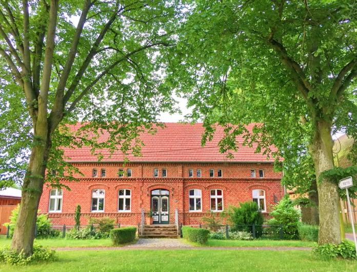 BuchholzRomantische Ferienwohnung Unter den Linden的一座大型红砖建筑,前面有树木