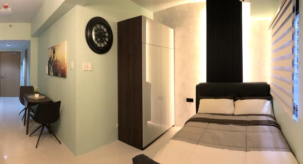 马尼拉MOA Pasay, Shore 3 Residences - Modern Luxury Condo的卧室配有一张床,墙上挂着一个钟