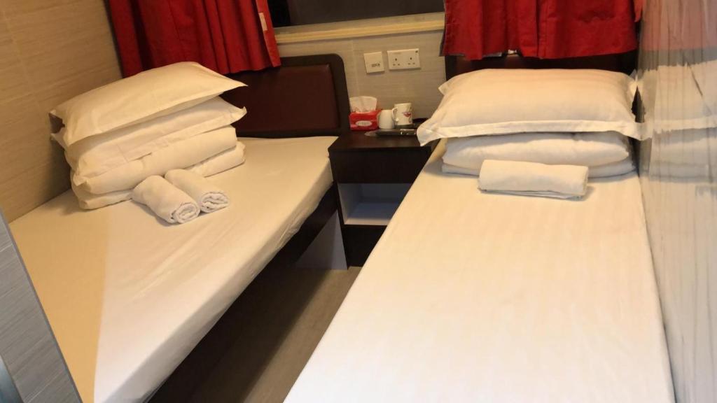 香港富都賓館 Fu Dou Guest House的两张位于酒店客房的床 - 带毛巾