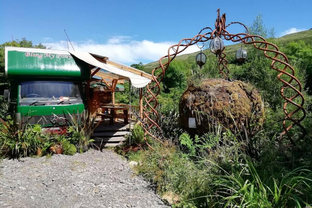 班特里Truck & Pod creative nature retreat.的停在小建筑旁边的绿色巴士