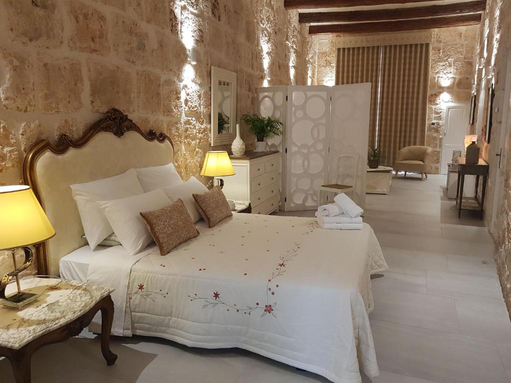 梅利哈Tal-Kampjin的卧室配有白色的床和石墙