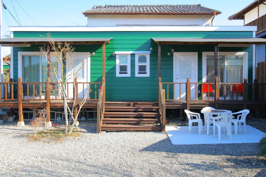 MifuneYuuwa Guesthouse的前面设有桌椅的绿色房子