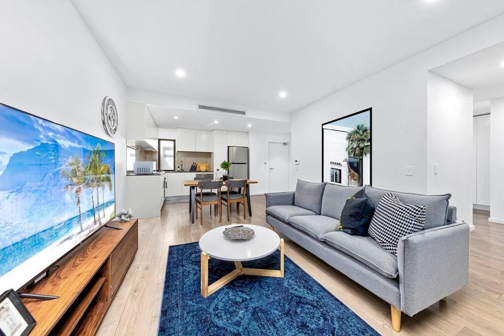 悉尼Centre of Newtown 2 Bed Apartment的带沙发和大屏幕电视的客厅