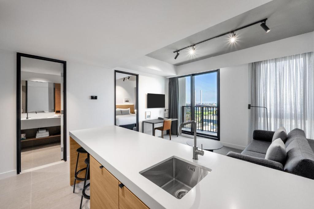 墨尔本Nesuto Docklands的公寓的厨房设有水槽和客厅。