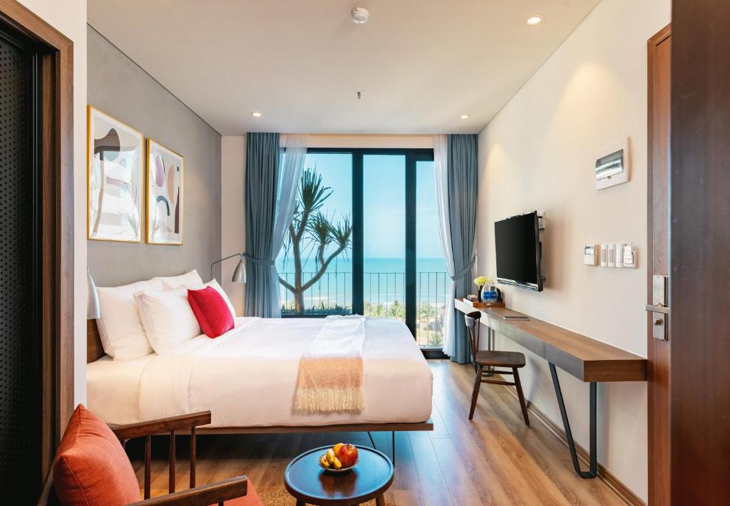 岘港The Glomad Danang Hotel的一间卧室配有一张床和一张书桌及电视