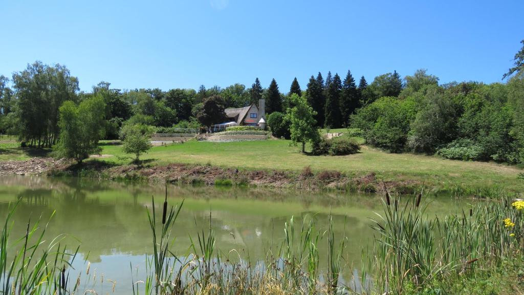 La Geneytouseles bois de saint Auvent的池塘旁小山上的房子