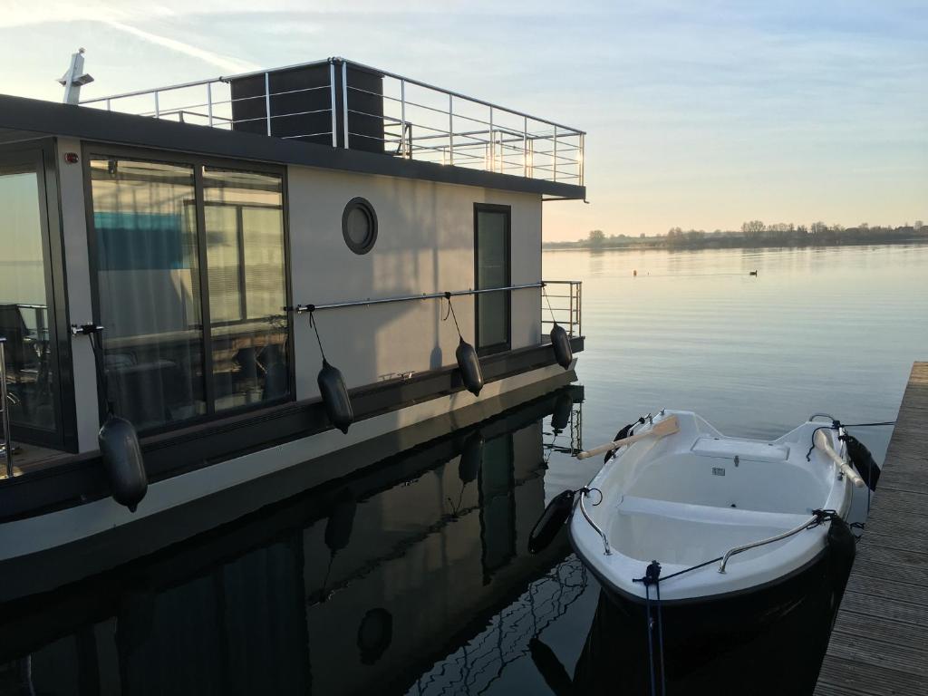 勒伯尔Modernes festliegendes Hausboot mit großzügiger Dachterrasse und Ruderboot的船停靠在水面上的码头