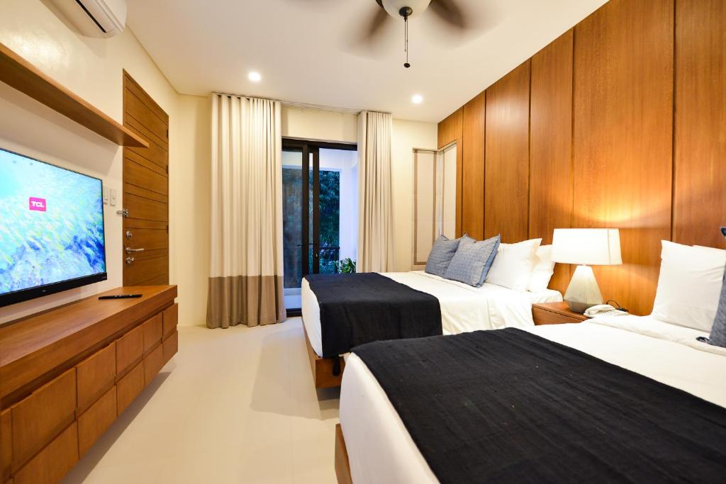 爱妮岛The Apartments at El Nido的酒店客房设有两张床和一台平面电视。