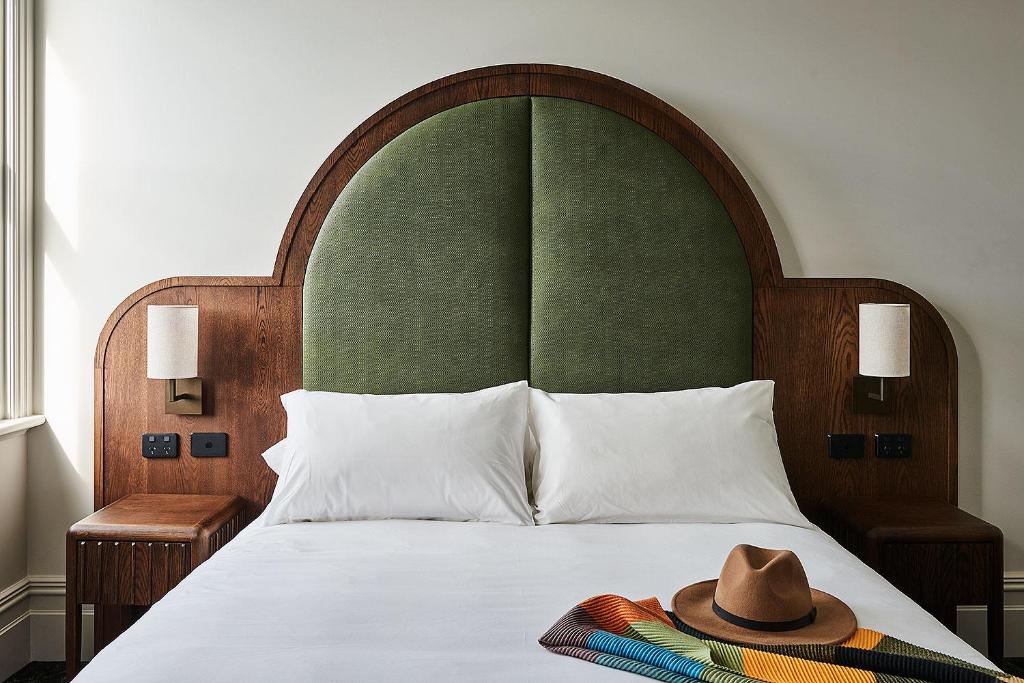 波塔灵顿Portarlington Grand Hotel的一张带绿色床头板的睡床,上面有帽子