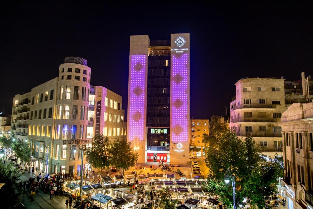 耶路撒冷Herbert Samuel Jerusalem的一座高大的建筑,晚上有紫色的灯光