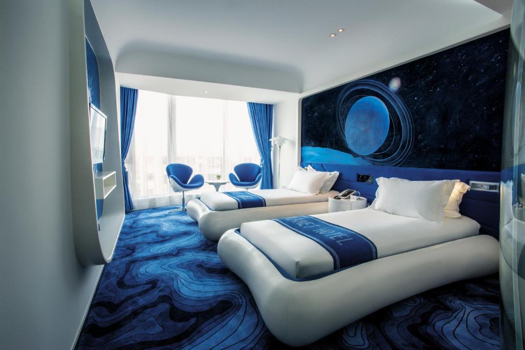 广州广州普兰内特概念酒店的蓝色地毯间内的两张床