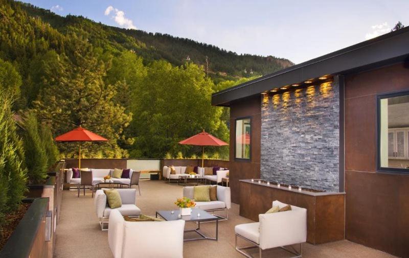 阿斯潘Luxury 2 Bedroom Downtown Aspen Vacation Rental With Access To A Heated Pool, Hot Tubs, Game Room And Spa的一座配有白色桌椅的庭院和一座建筑