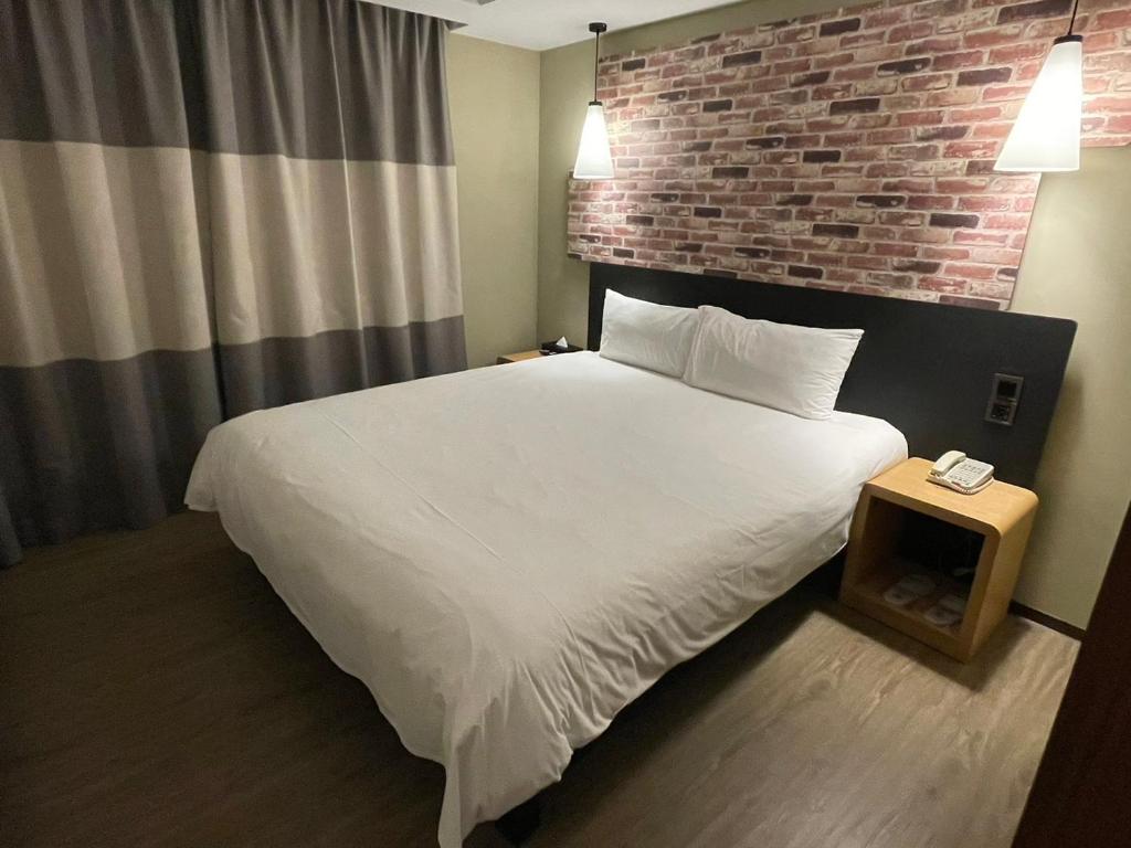 台北苓旅中山馆-Lininn ZhongShan的卧室配有白色的床和砖墙