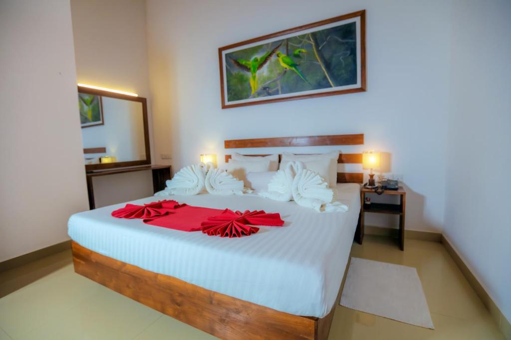 锡吉里亚Sigiri Asna Nature Resort的一间卧室配有一张大白色床,上面有红色的弓
