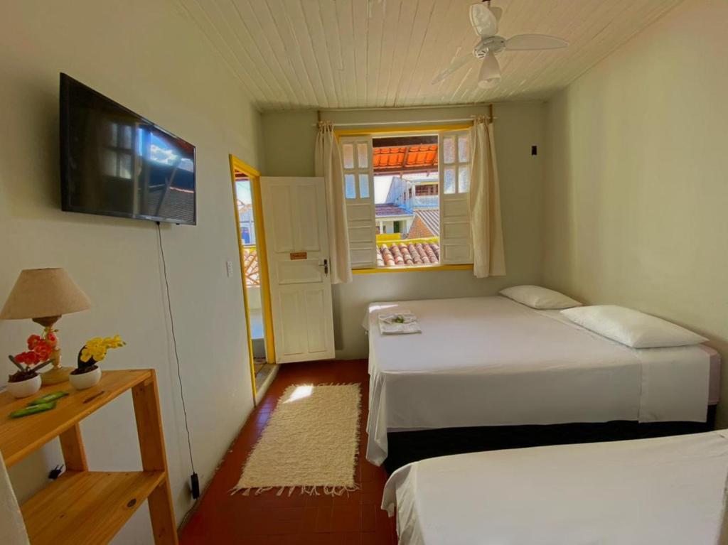 卡拉韦拉斯Pousada do beco的一间卧室设有两张床、一台电视和一扇窗户。