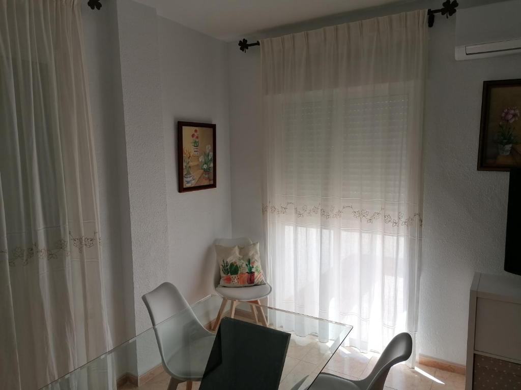 塔韦尔纳斯Alojamiento las Dunas的客房设有玻璃桌、椅子和窗户。