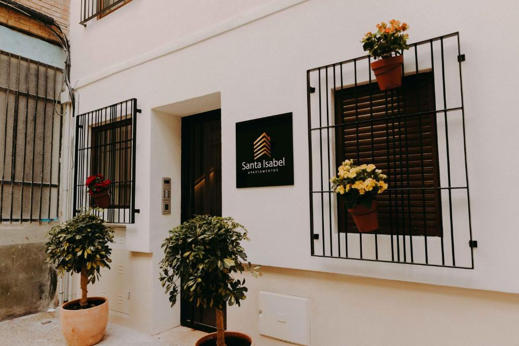 穆尔西亚Apartamentos Santa Isabel的门上布满盆栽植物的白色建筑