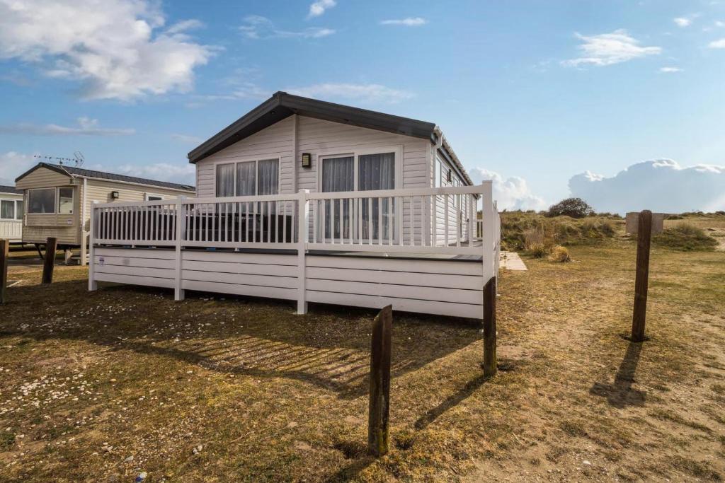 BenacreBeautiful 8 Berth Lodge For Hire At Kessingland Beach In Suffolk Ref 90012td的田野上的小房子,有栅栏