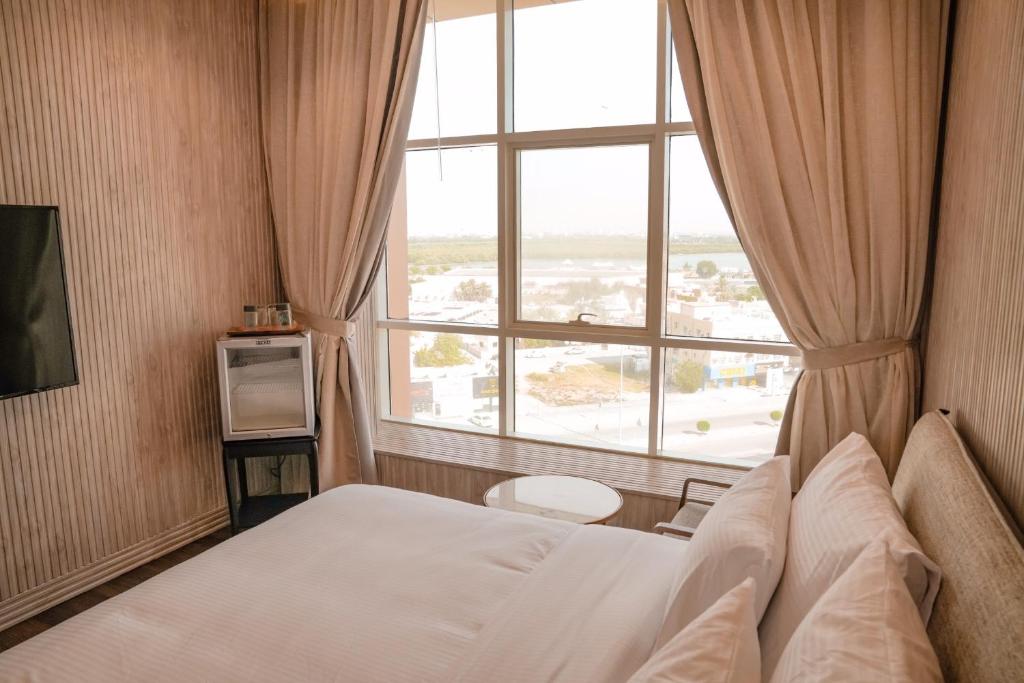 拉斯阿尔卡麦M14 Hotel Apartment的酒店客房设有一张床和一个大窗户