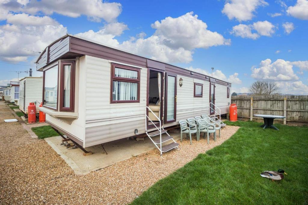 亨斯坦顿Dog Friendly 6 Berth Static Caravan By The Beach In Hunstanton Ref 13008l的一张带桌椅的白色小拖车