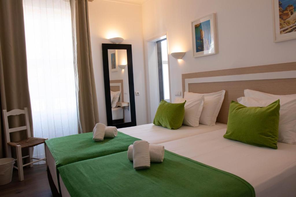 阿尔布费拉Albufeira Beach Hotel by Kavia的一间卧室配有两张带绿床单和镜子的床