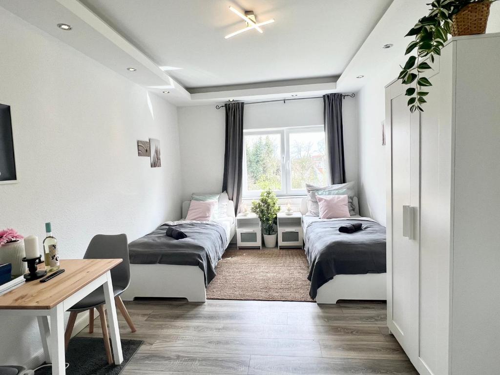 不来梅港Helle, gemütliche Ferienwohnung in Bremerhaven的客房设有三张床、一张书桌和一个窗户。