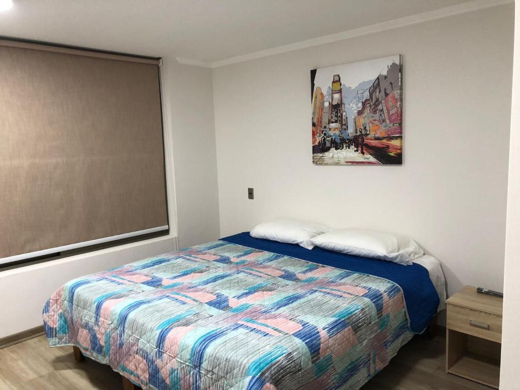 伊基克ALTOS DE HUAYQUIQUE的卧室配有一张床,墙上挂有绘画作品