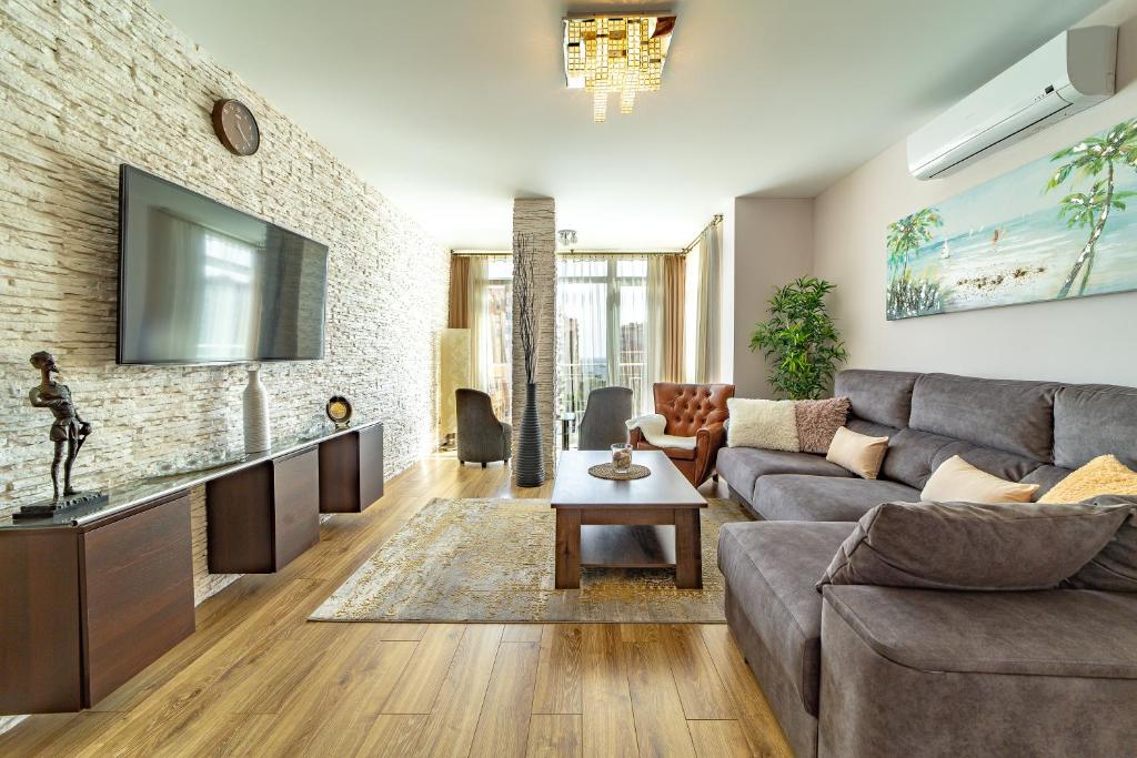 马拉加Perla de Malagueta的客厅配有沙发和砖墙电视