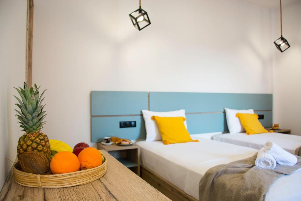 卡沃斯Big Max Guesthouse的一间设有两张床的房间和一张桌子上的一篮水果