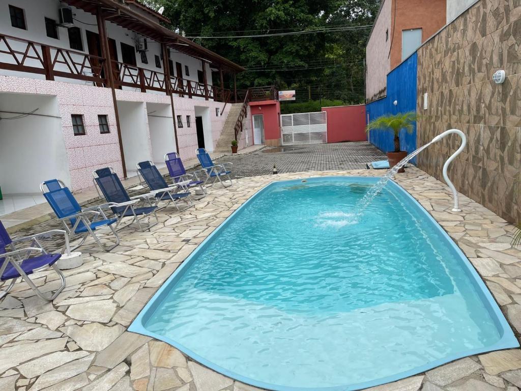 朱奎Pousada Canto Juquehy的一座带椅子的大型游泳池和一座建筑