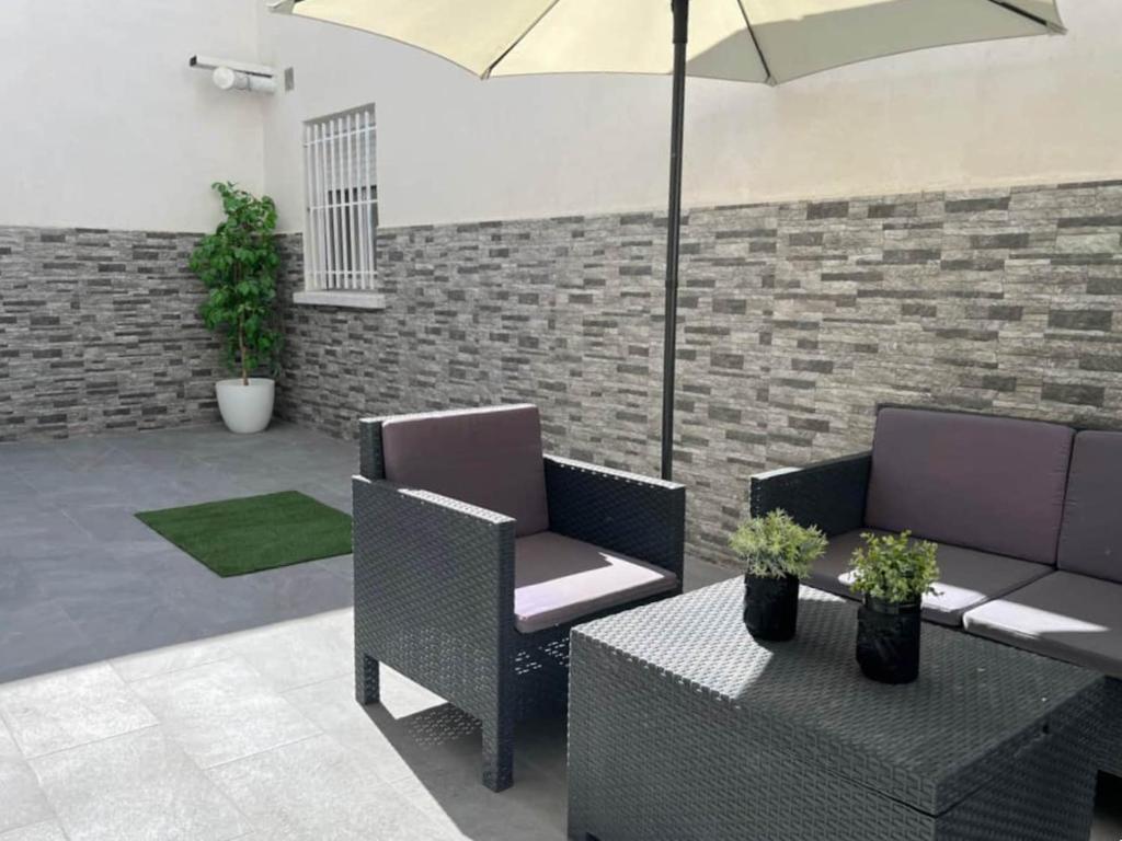 Carabanchel AltoLuminoso apartamento con precioso y amplio patio的庭院配有两把椅子、一张桌子和一把遮阳伞