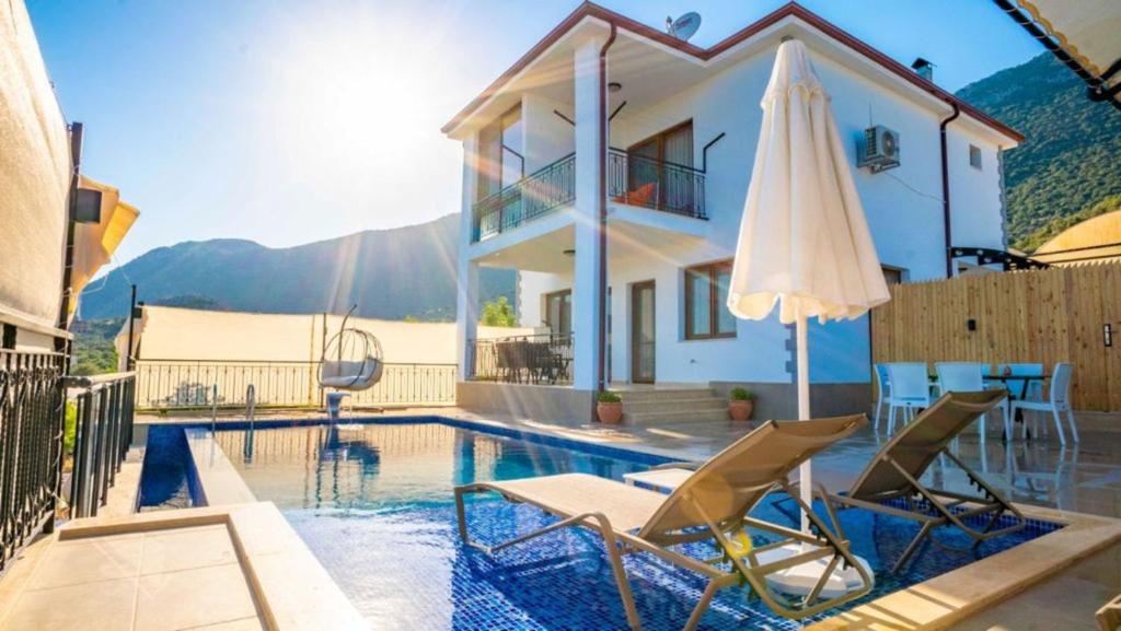 卡斯VİLLA TANYERİ的别墅 - 带游泳池、2把椅子和遮阳伞