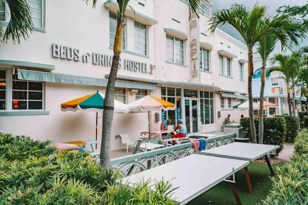 迈阿密海滩住宿加饮品酒店的大楼前有桌子和遮阳伞的酒店