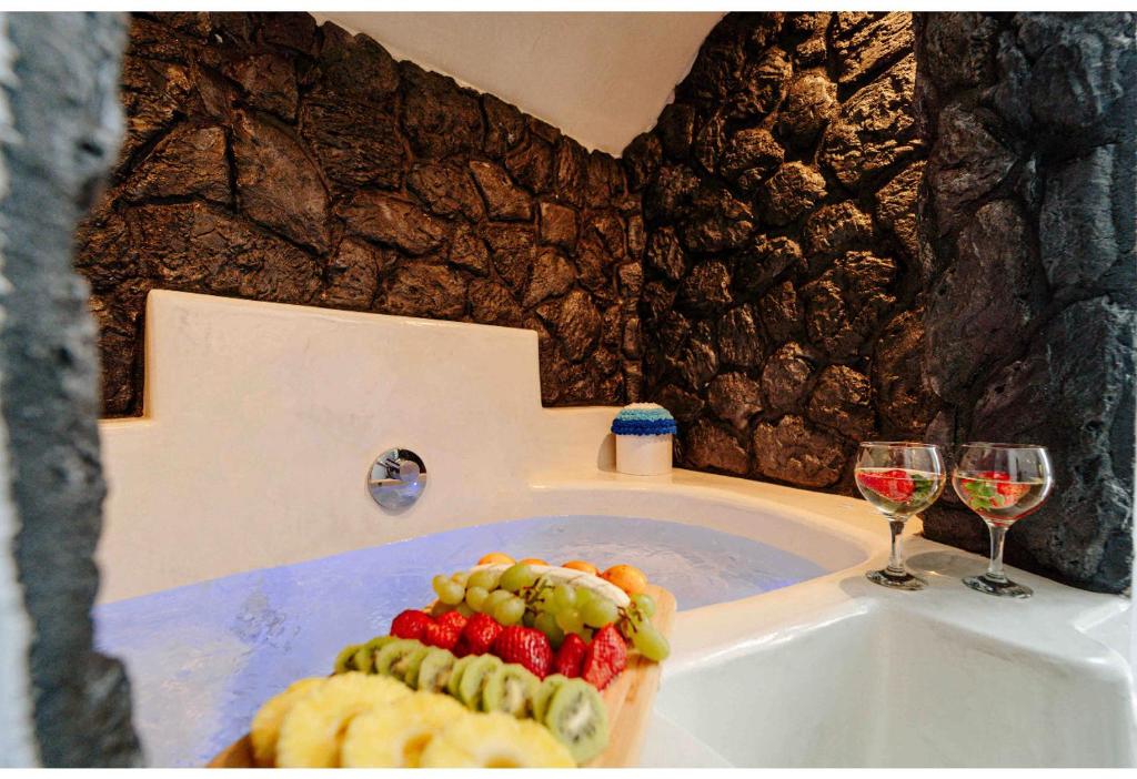 Éxo Goniáaletrivillas的浴缸内备有两杯葡萄酒和水果
