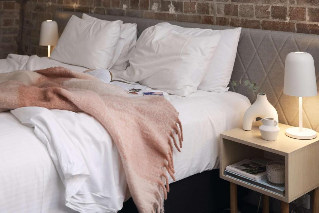悉尼阿尔提莫酒店的一张带白色枕头的床和一张毯子