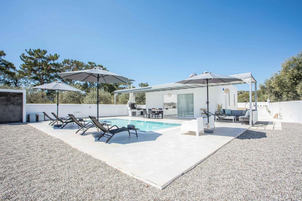 拉多斯VillaPhysis with Private Pool的一个带遮阳伞和椅子的游泳池和一个庭院